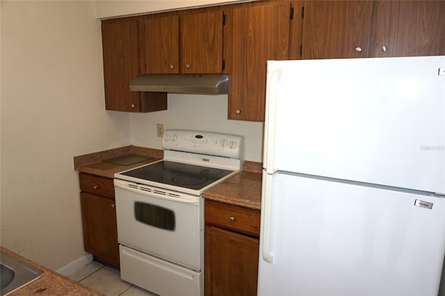 kitchen with brown cabinets, white appliances, light tile patterned flooring, and under cabinet range hood