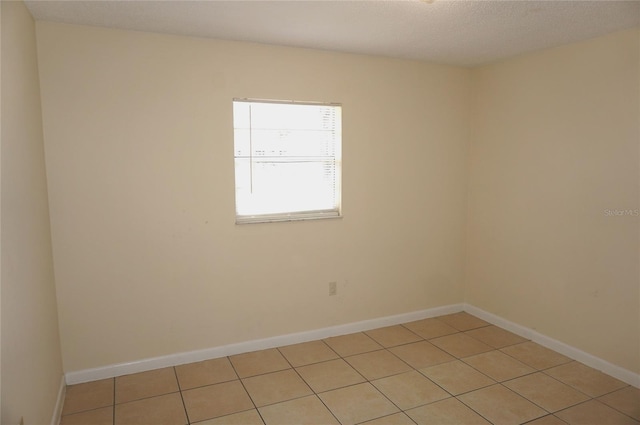 empty room featuring light tile patterned flooring and baseboards