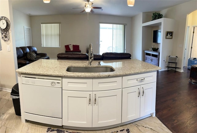 kitchen with dishwasher, sink, light wood-type flooring, light stone countertops, and white cabinets