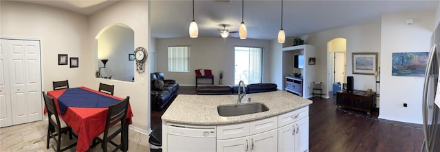 kitchen with decorative light fixtures, dark hardwood / wood-style floors, sink, light stone countertops, and white cabinets