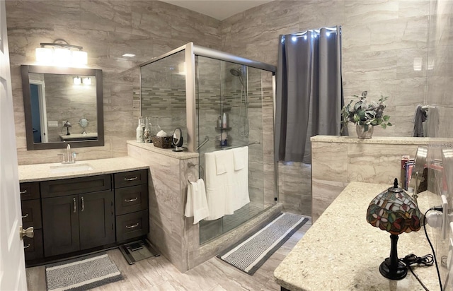 bathroom featuring a shower with door, vanity, and tile walls