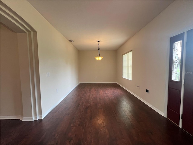 unfurnished dining area with dark wood-style flooring and baseboards