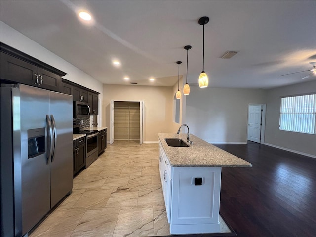 kitchen with stainless steel appliances, a sink, baseboards, stone countertops, and a ceiling fan