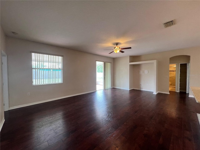 spare room with arched walkways, ceiling fan, dark wood-type flooring, and baseboards