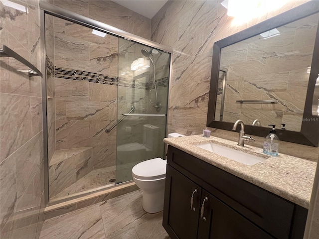 bathroom with tile walls, a stall shower, toilet, and vanity