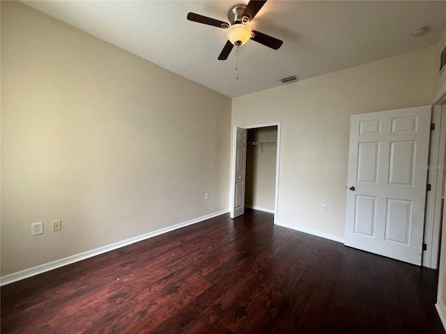 unfurnished bedroom featuring dark wood-style flooring, baseboards, a closet, and a ceiling fan