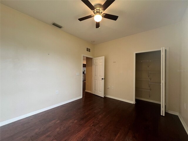 unfurnished bedroom with dark wood-style floors, a closet, baseboards, and ceiling fan