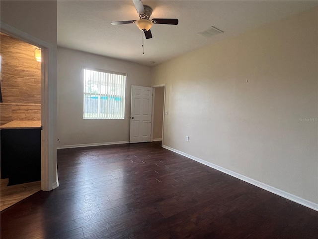 unfurnished bedroom featuring dark wood-style floors, baseboards, and a ceiling fan
