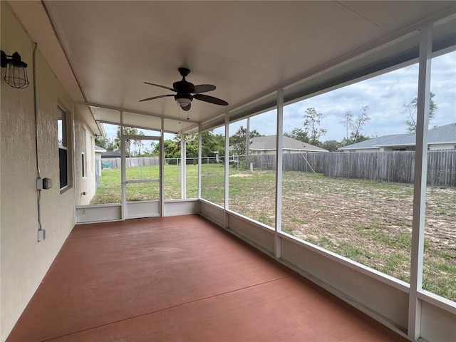 unfurnished sunroom featuring a ceiling fan and plenty of natural light