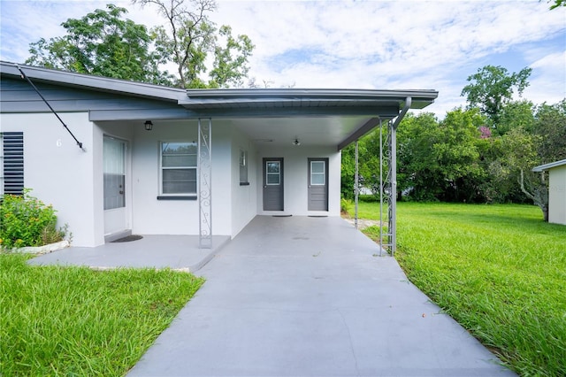 view of exterior entry featuring a lawn and a carport