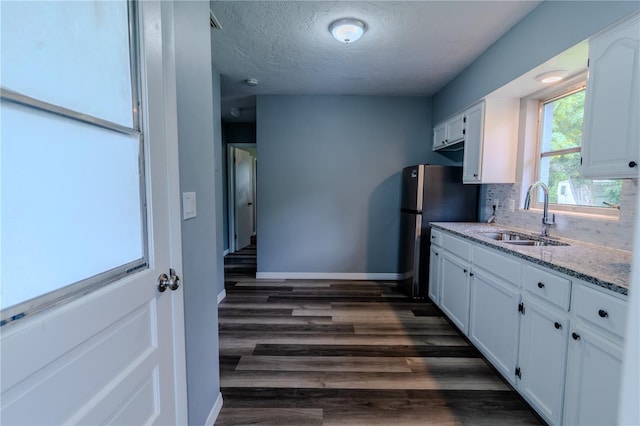 kitchen with light stone counters, sink, white cabinetry, and backsplash