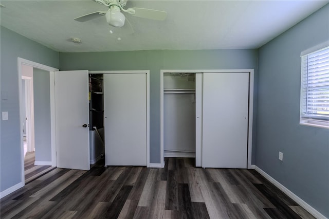 unfurnished bedroom with ceiling fan, two closets, and dark hardwood / wood-style floors