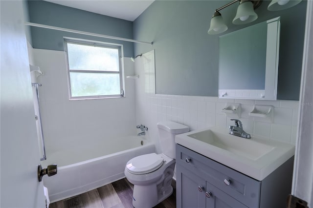 full bathroom with toilet, tiled shower / bath, tile walls, vanity, and hardwood / wood-style flooring