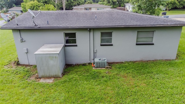 rear view of house with cooling unit and a lawn