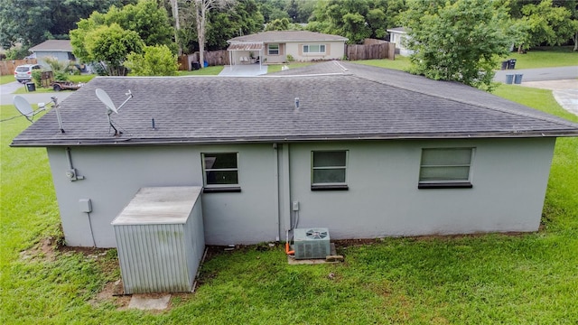 rear view of property with central AC unit and a lawn