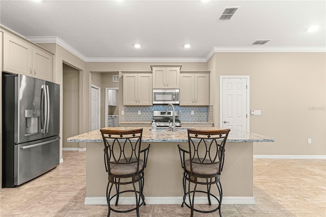 kitchen featuring light stone counters, stainless steel appliances, and an island with sink