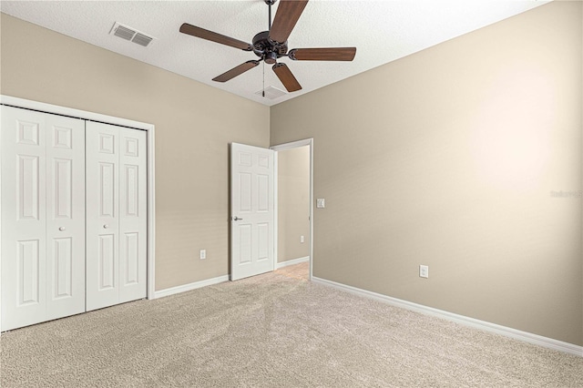 unfurnished bedroom featuring light carpet, a textured ceiling, ceiling fan, and a closet