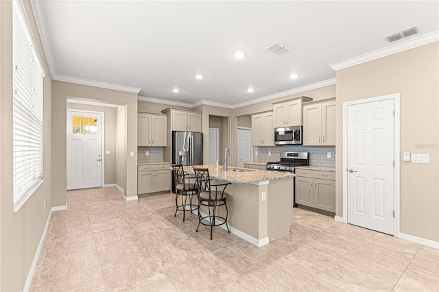 kitchen featuring appliances with stainless steel finishes, an island with sink, sink, a breakfast bar area, and decorative backsplash