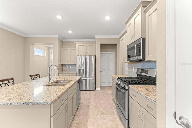 kitchen featuring a kitchen bar, sink, tasteful backsplash, an island with sink, and stainless steel appliances