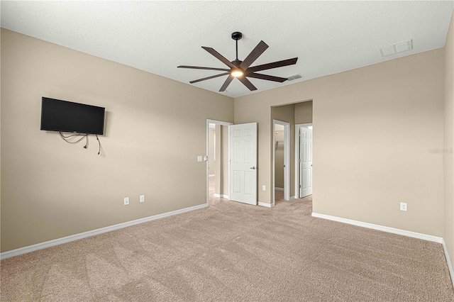 unfurnished bedroom with ceiling fan, light carpet, and a textured ceiling