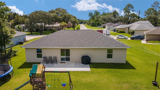 rear view of house with a patio, a playground, a yard, and a trampoline