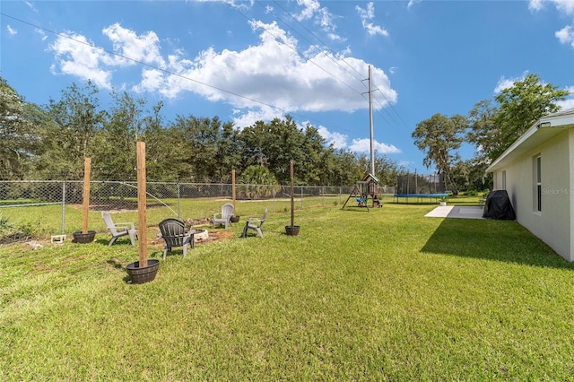 view of yard featuring a playground and a trampoline