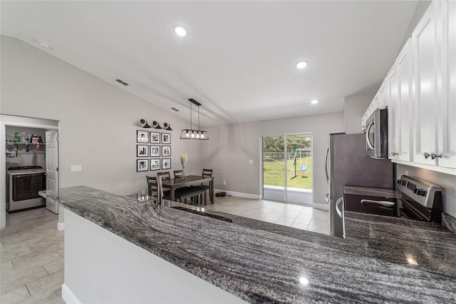 kitchen with white cabinets, appliances with stainless steel finishes, lofted ceiling, dark stone countertops, and hanging light fixtures