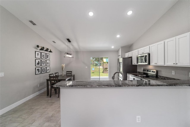 kitchen featuring appliances with stainless steel finishes, white cabinetry, dark stone countertops, kitchen peninsula, and vaulted ceiling