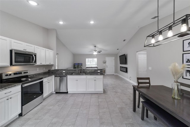 kitchen with kitchen peninsula, hanging light fixtures, appliances with stainless steel finishes, white cabinets, and lofted ceiling