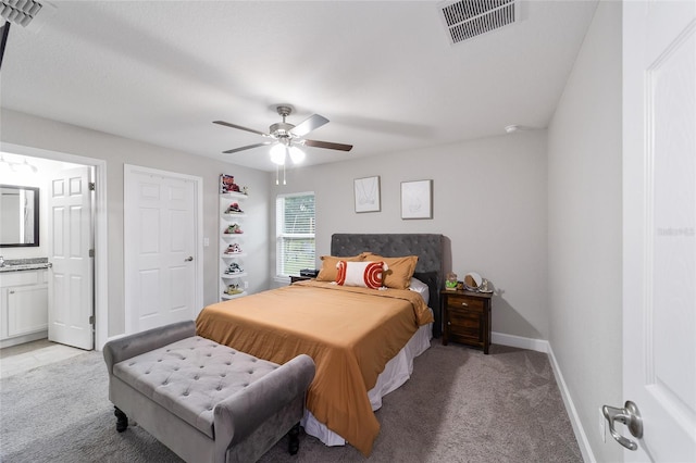 bedroom featuring ceiling fan, connected bathroom, and light carpet