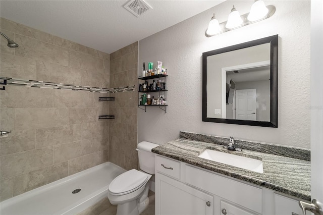 bathroom with tiled shower, toilet, and vanity