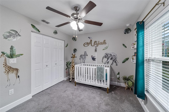 carpeted bedroom featuring ceiling fan, a closet, and a crib