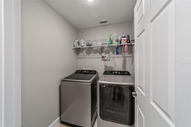 washroom with washing machine and clothes dryer and a textured ceiling