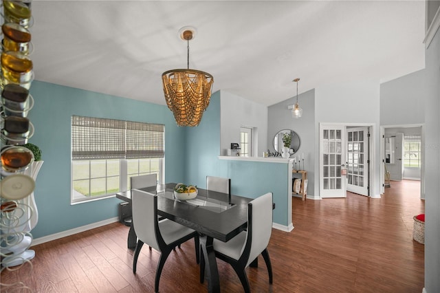 dining room with lofted ceiling, dark hardwood / wood-style floors, a chandelier, and french doors