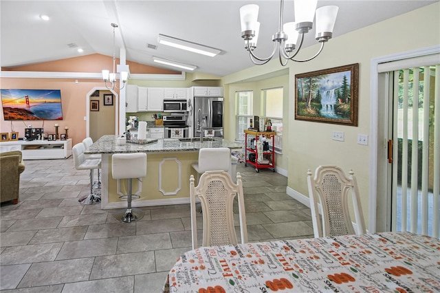 dining space featuring vaulted ceiling, an inviting chandelier, and sink