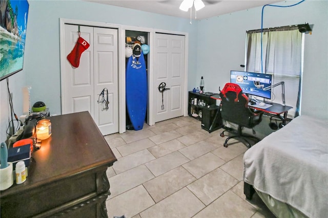 tiled bedroom featuring two closets and ceiling fan