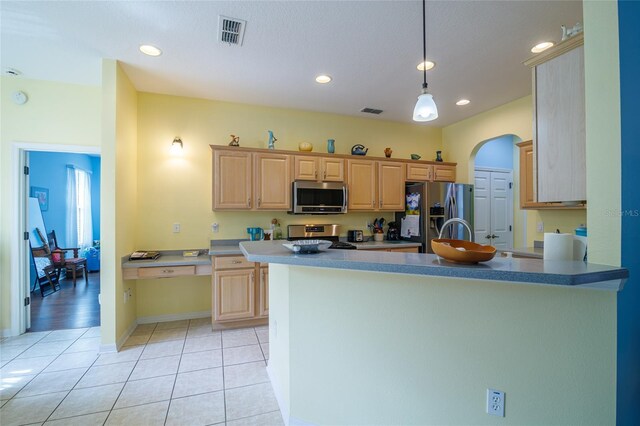 kitchen with light brown cabinets, kitchen peninsula, stainless steel appliances, and light tile patterned floors