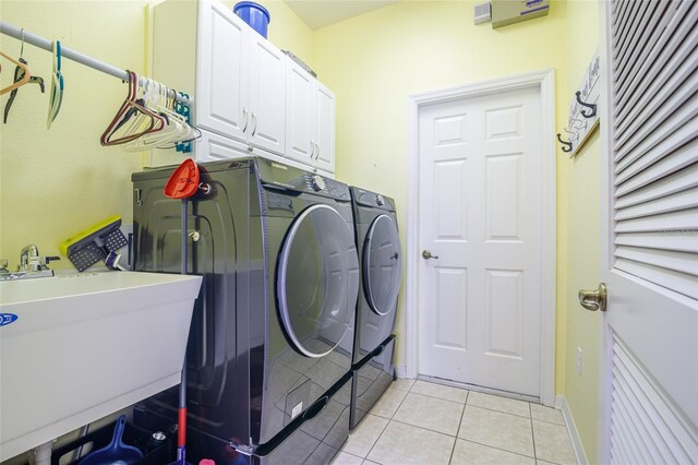 laundry room with sink, washer and dryer, cabinets, and light tile patterned floors