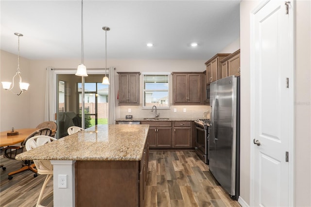 kitchen with a kitchen breakfast bar, pendant lighting, sink, a center island, and stainless steel appliances