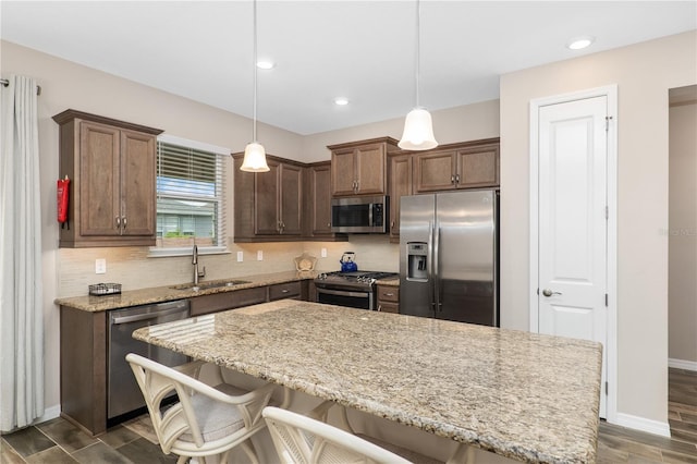 kitchen with a breakfast bar, hanging light fixtures, and appliances with stainless steel finishes