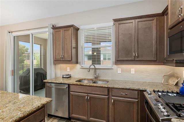 kitchen featuring light stone counters, sink, appliances with stainless steel finishes, and tasteful backsplash