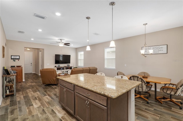 kitchen featuring pendant lighting, dark hardwood / wood-style floors, light stone countertops, and dark brown cabinetry