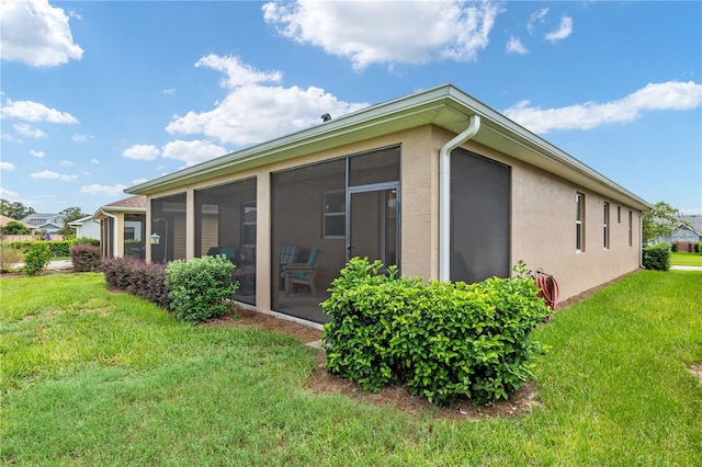 rear view of property featuring a lawn and a sunroom