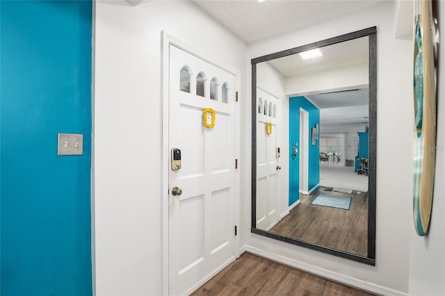 doorway to outside with dark hardwood / wood-style flooring and a textured ceiling