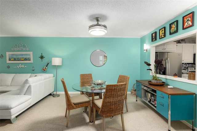 dining space featuring light colored carpet and a textured ceiling