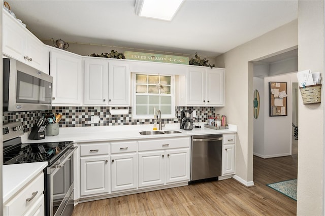 kitchen with sink, white cabinetry, light hardwood / wood-style flooring, stainless steel appliances, and backsplash