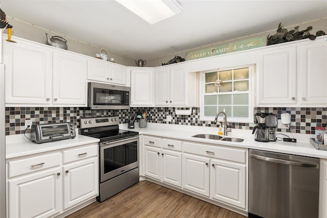 kitchen with sink, white cabinetry, tasteful backsplash, light hardwood / wood-style flooring, and stainless steel appliances