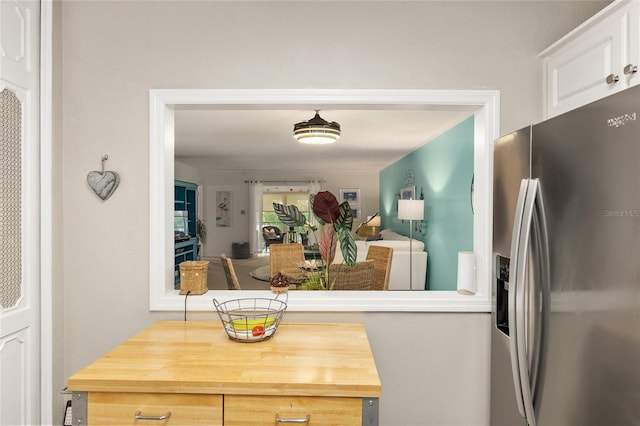 kitchen with white cabinets, stainless steel refrigerator with ice dispenser, and wooden counters