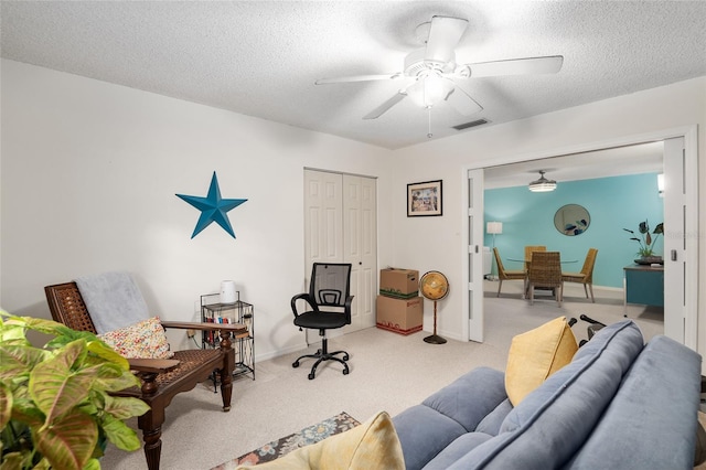 living room with ceiling fan, light colored carpet, and a textured ceiling