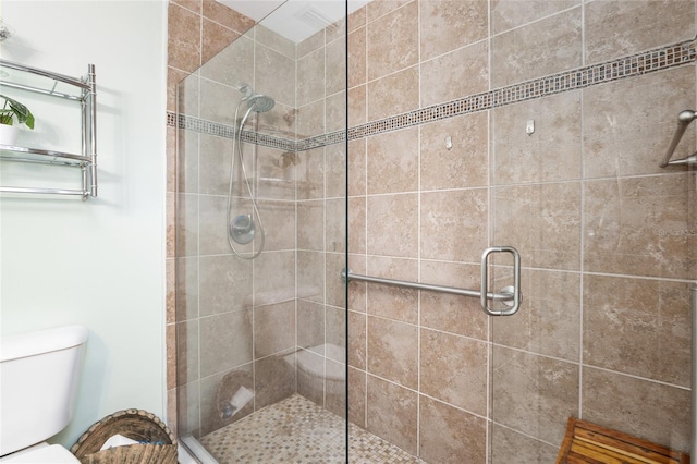 bathroom featuring a shower with door and toilet